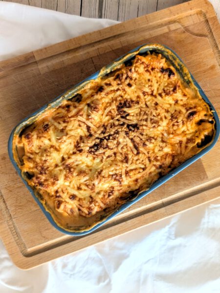 Cheesy Bolognese Pasta Bake Käsiger Bolognese Nudelauflauf auf einem Holzbrett, Comfort-Food an kalten Tagen