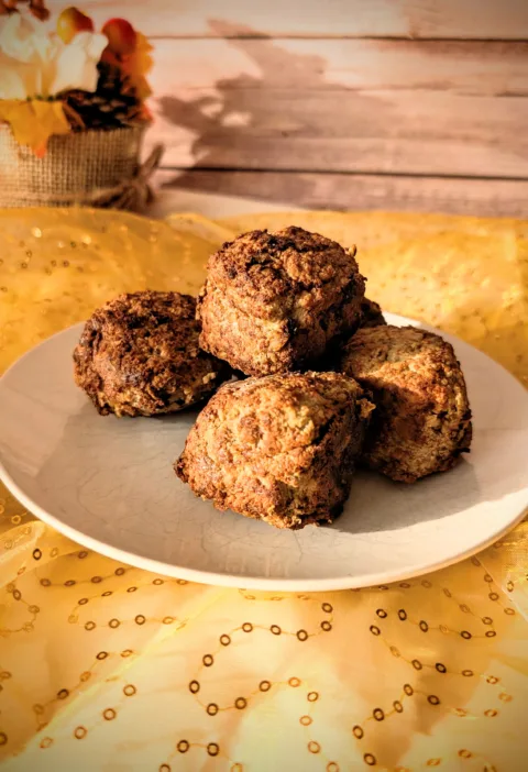 Saftige Hackbällchen aus gemischtem Hackfleisch auf einem weißen Teller, goldbraun gebraten und locker aufgeschichtet, fotografiert auf gelbem Stoff vor hellem Holz-Hintergrund.
