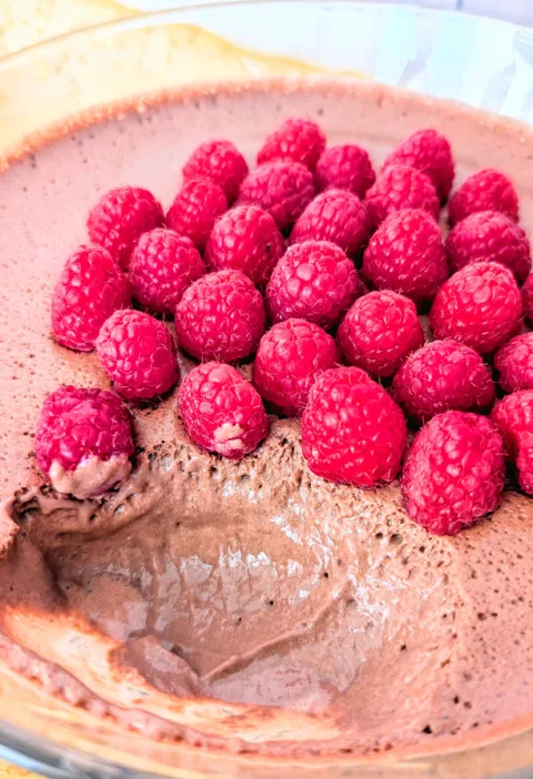 Cremige High-Protein Mousse au Chocolat in einer Glasschale, luftig aufgeschlagen aus Quark und Frischkäse und mit frischen Himbeeren dekoriert – ein eiweißreiches Frühstück zum Vorbereiten.