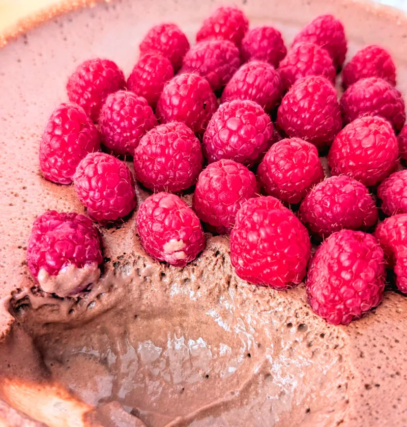 Cremige High-Protein Mousse au Chocolat in einer Glasschale, luftig aufgeschlagen aus Quark und Frischkäse und mit frischen Himbeeren dekoriert – ein eiweißreiches Frühstück zum Vorbereiten.