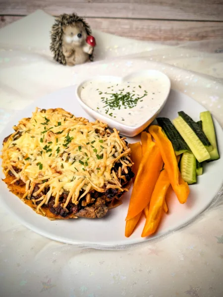 Überbackene Süßkartoffel mit würziger BBQ-Hackfleischfüllung, Kichererbsen, Jalapeños und goldbraun geschmolzenem Käse, serviert mit cremigem Dip und frischen Gemüsesticks.