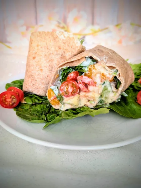 Hähnchen-Wrap mit Mandarine, Avocado, Ei, Tomaten, Blattsalat und cremiger Joghurt-Sauce auf einem Teller angerichtet. Der aufgeschnittene Wrap zeigt die frische, sommerliche Füllung mit saftigem Hähnchen, knackigem Gemüse und fruchtigen Mandarinenstücken.