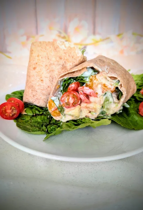 Hähnchen-Wrap mit Mandarine, Avocado, Ei, Tomaten, Blattsalat und cremiger Joghurt-Sauce auf einem Teller angerichtet. Der aufgeschnittene Wrap zeigt die frische, sommerliche Füllung mit saftigem Hähnchen, knackigem Gemüse und fruchtigen Mandarinenstücken.